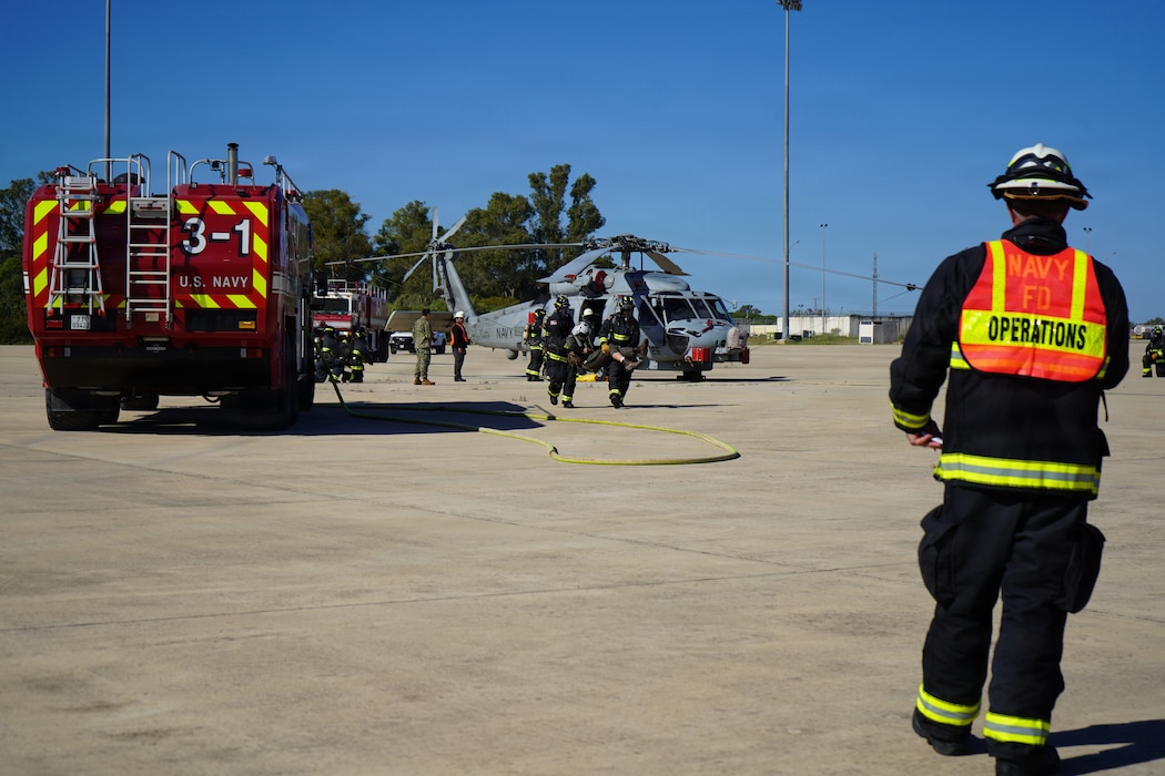 Fire and Emergency Services personnel transport a simulated casualty during an Air Mishap exercise at Naval Station Rota, May 20, 2026. The exercise brought together first responders and medical personnel from Naval Medical Readiness and Training Command (NMRTC) Rota to practice casualty triage, patient movement, and emergency response procedures in a realistic training environment. The training enhanced coordination among responding agencies and strengthened the readiness of Navy Medicine personnel to provide lifesaving care and medical support during operational, contingency, and emergency response missions. (U.S. Navy photo by Lt. Vanessa Bernales)