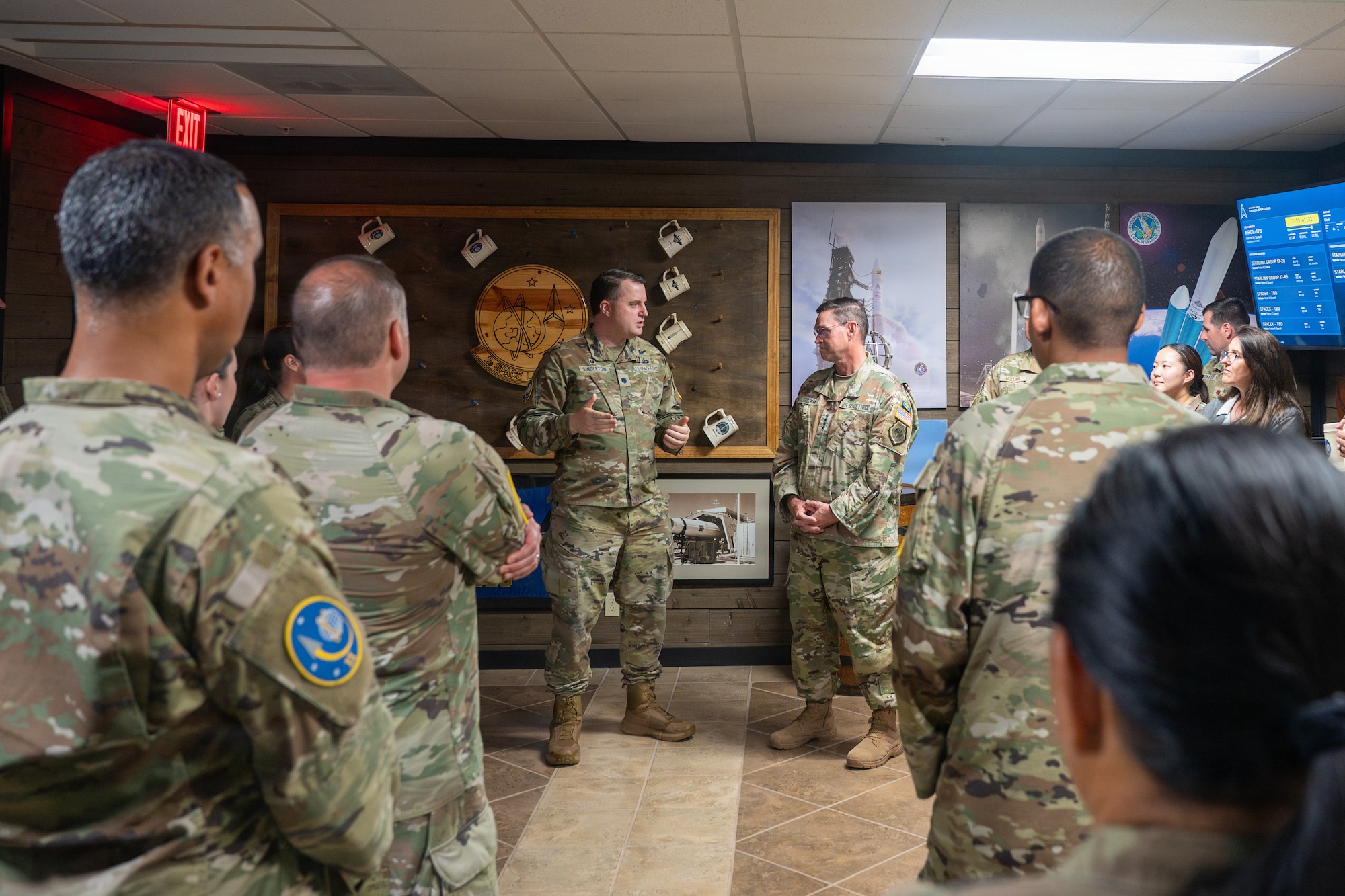 An Space Force officer briefs a general in a Viking style heritage room filled with military members and civilians.