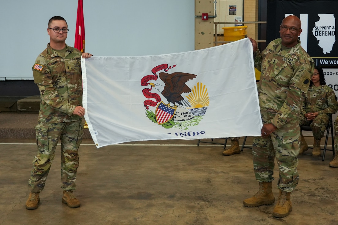 1st Lt. Colin Kehoe, who will lead the approximately 70 Soldiers of the 233rd Military Police Co. on its deployment to Alaska, displays the State of Illinois Flag with Maj. Gen. Rodney Boyd, The Adjutant General of Illinois and Commander of the Illinois National Guard, during the unit’s June 7 mobilization ceremony on Camp Lincoln in Springfield.