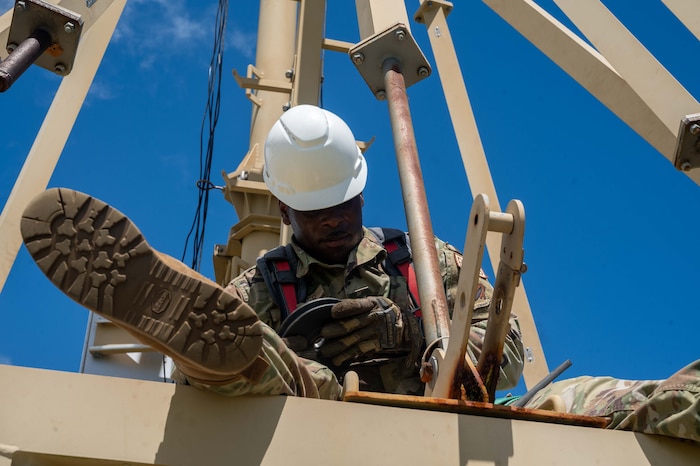 an airman wears a white hat while working on an antenna