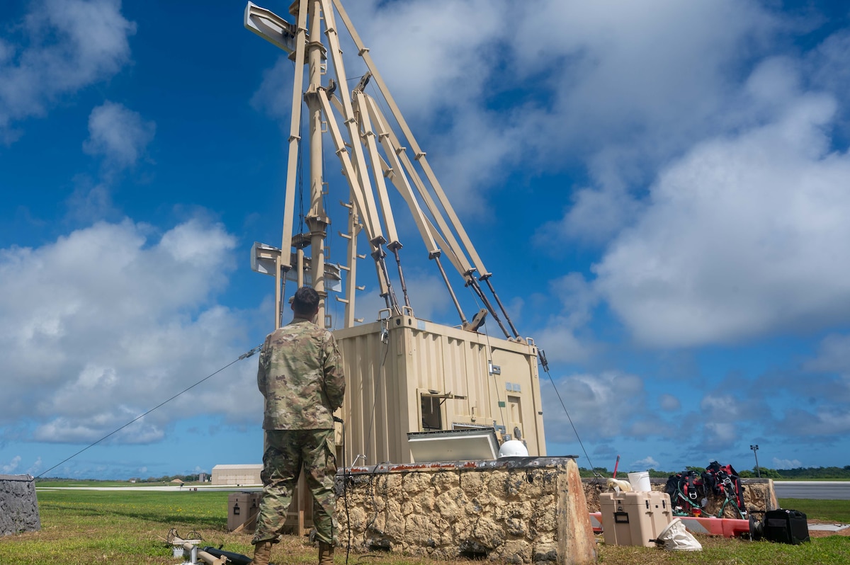 an airman looks at an antenna while calibrating it