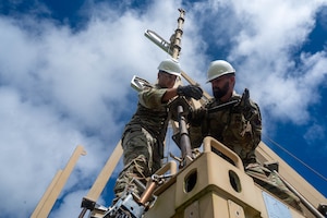 two airmen tighten a bolt on a glide slope antenna
