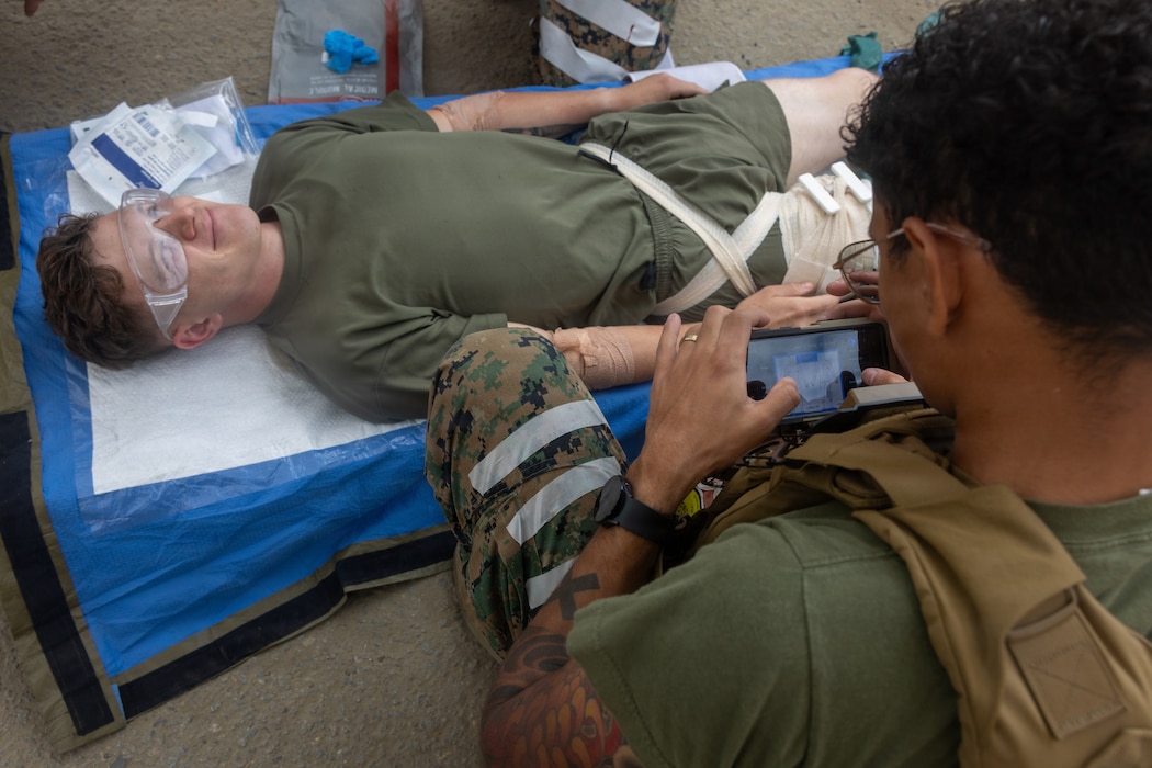 260612-M-HP122-1009 U.S. Navy Petty Officer 2nd Class Matteo Candanoza, a hospital corpsman with 1st Medical Battalion, 1st Marine Logistics Group, utilizes a Battlefield Assisted Trauma Documentation Kit on an End User Device while conducting a blood transfusion on a simulated patient during a Valkyrie course on Marine Corps Base Camp Pendleton, California, June 12, 2026.  Sailors utilized a Battlefield Assisted Trauma Documentation Kit which enables them to log injury types, treatments, and vital signs via a touchscreen EUD, even in disconnected environments. The course focused on learning and performing fresh whole blood collection and transfusions on simulated patients, preparing them for forward deployed and austere environments. (U.S. Marine Corps photo by Sgt. Mary Torres)