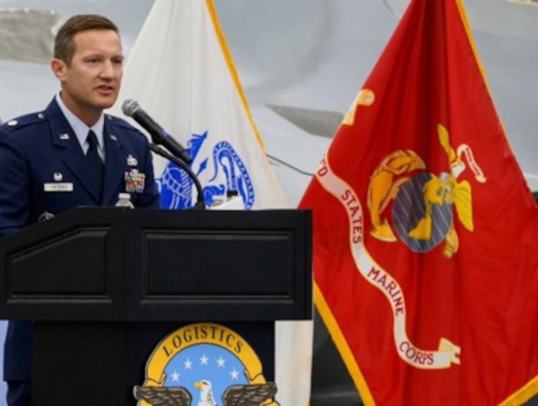 Air force Lt. Col. standing at a podium during a ceremony delivering remarks to attendees seated in the audience.