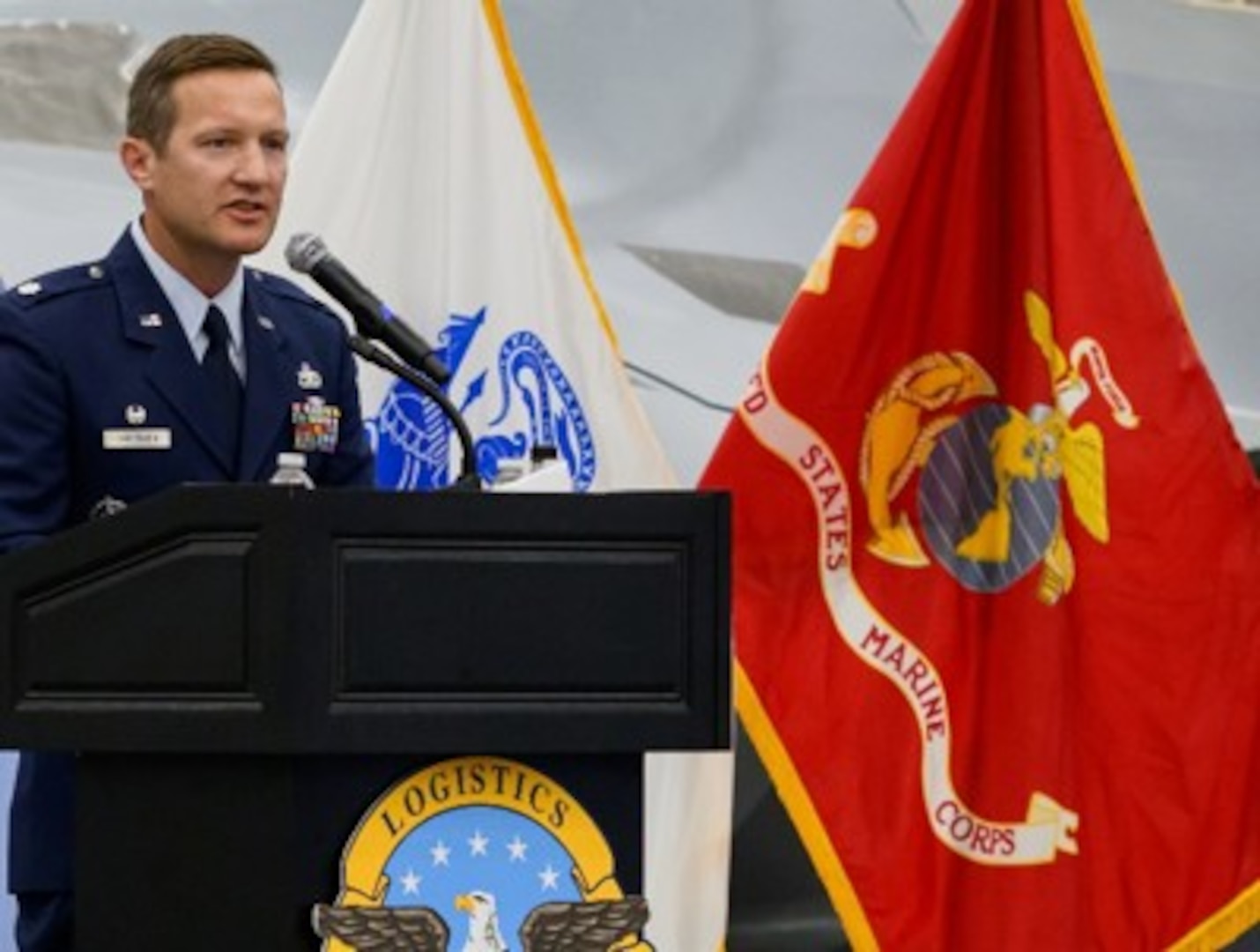 Air force Lt. Col. standing at a podium during a ceremony delivering remarks to attendees seated in the audience.