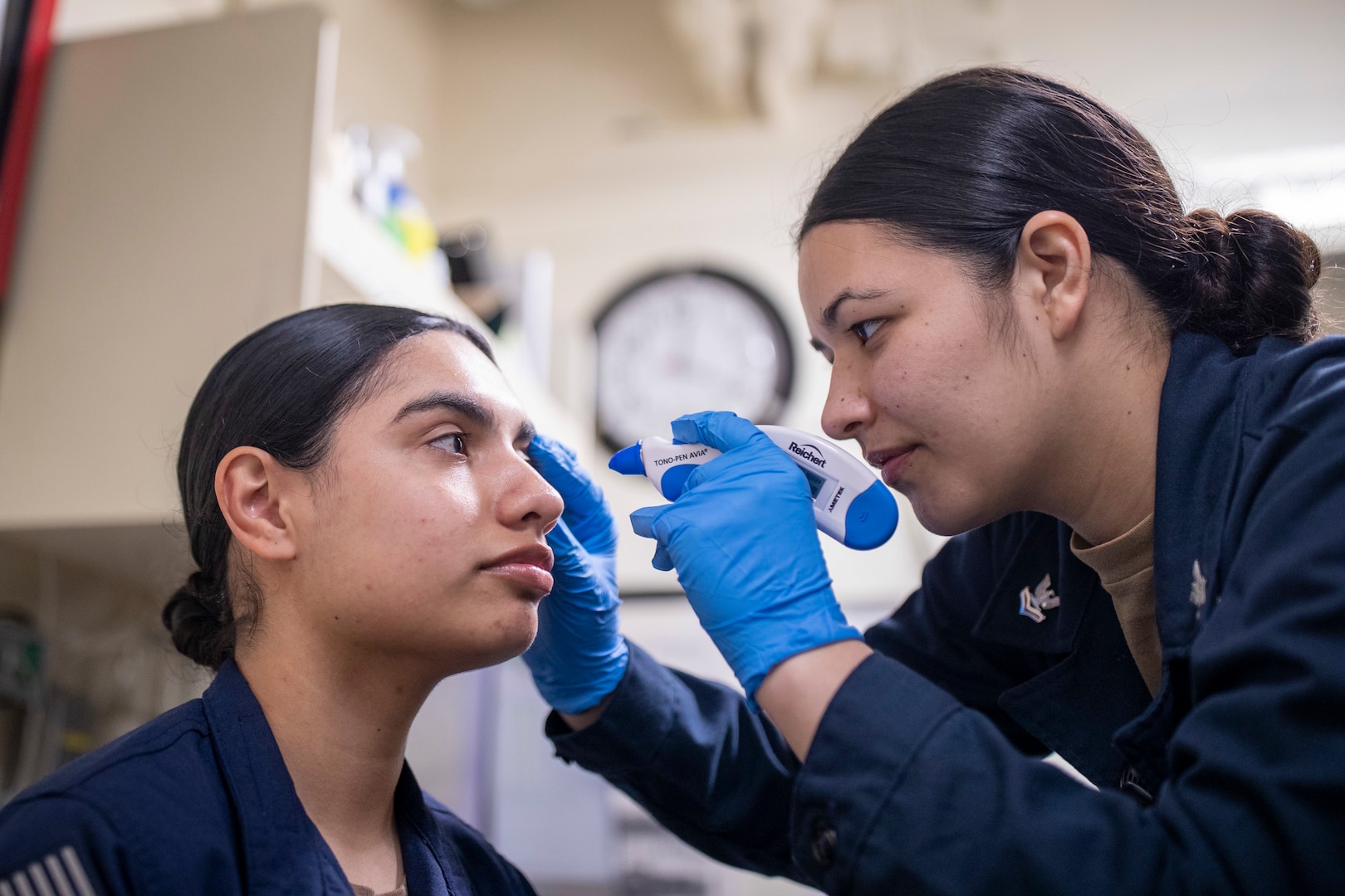 Service member examines the eye of another service member.