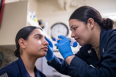 Service member examines the eye of another service member.