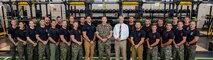 Nicholas Gounaris, the director of strength and conditioning with Warrior Athlete Readiness and Resilience, center left, U.S. Marine Corps Col. Robert McCarthy III, the commanding officer of The Basic School, center, and Brad Brimhall, the branch head with Warrior Athlete Readiness and Resilience, center right, pose for a group photo with the Martial Arts Fitness and Center of Excellence staff at Ramer Hall on Marine Corps Base Quantico, Virginia, June 16, 2026. The Ramer Hall facility upgrades strengthen the vital partnerships between TBS, Basic Officer Course, MAFCE and other units. This collaboration establishes a sustainable foundation for optimizing human performance and resiliency across the entire Marine Corps. (U.S. Marine Corps photo by Lance Cpl. Lynsee Avila-Ramirez)