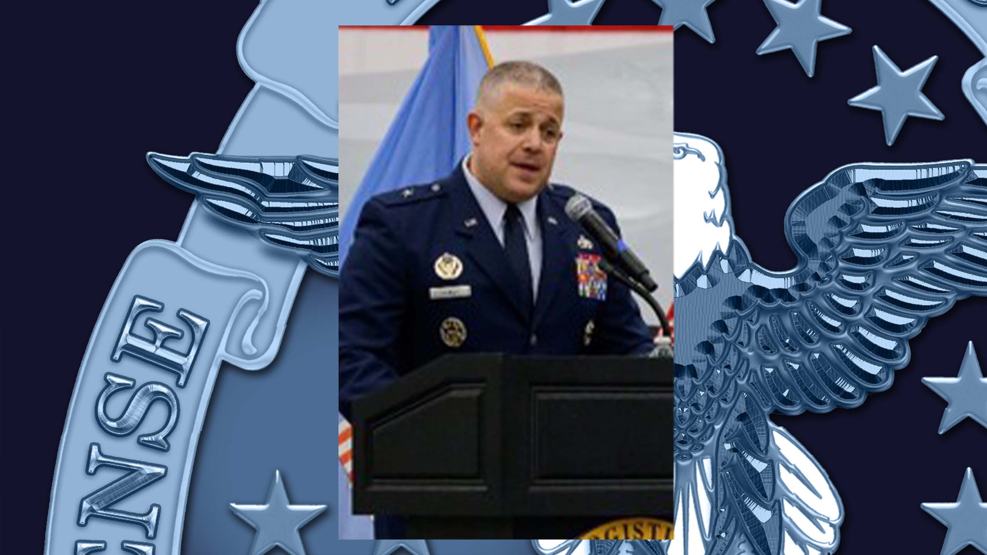 Air Force one-star General standing at a podium delivering remarks to audience members/attendees during a change of command ceremony