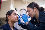 Petty Officer 2nd Class Venizia Lopez, from San Diego, preforms a intraocular pressure test on Petty Officer 3rd Class Kathie Barrientes, from Brownsville, Texas, aboard amphibious assault carrier USS Tripoli. (U.S. Navy photo by Seaman Paul LeClair)