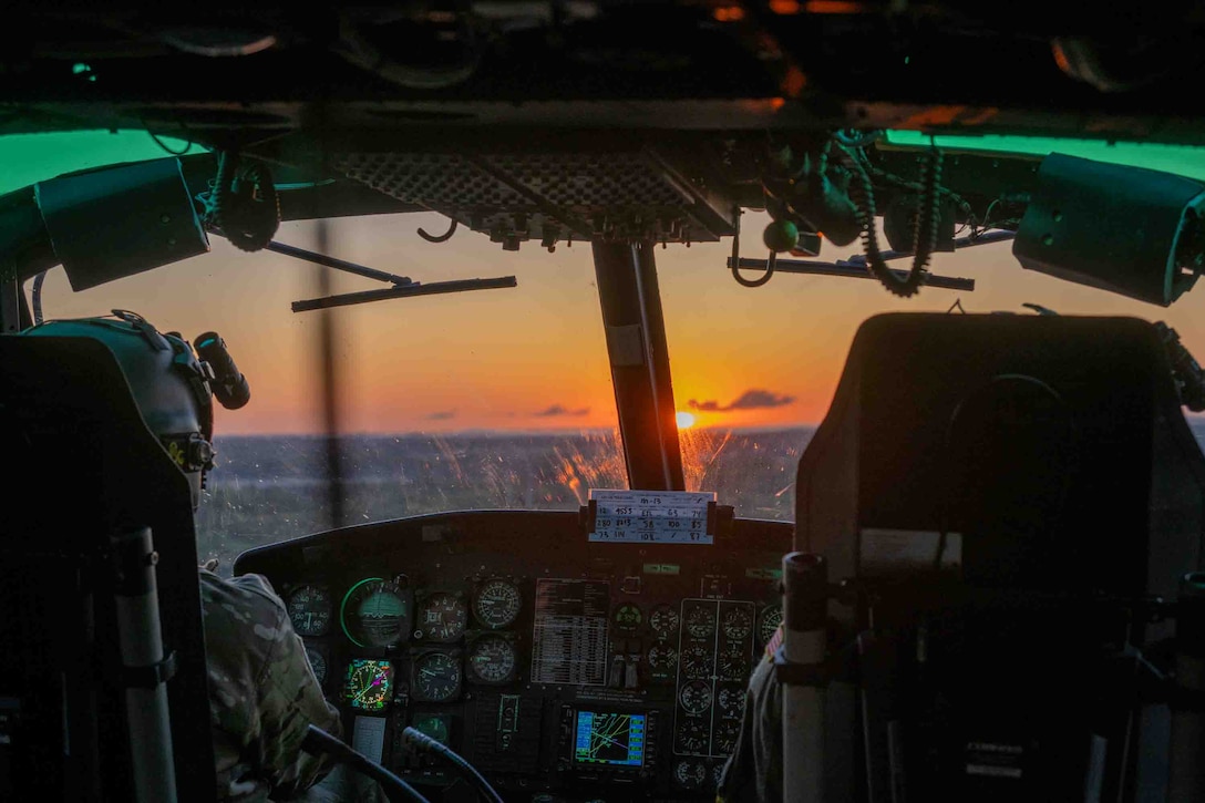 Service members fly in a helicopter.
