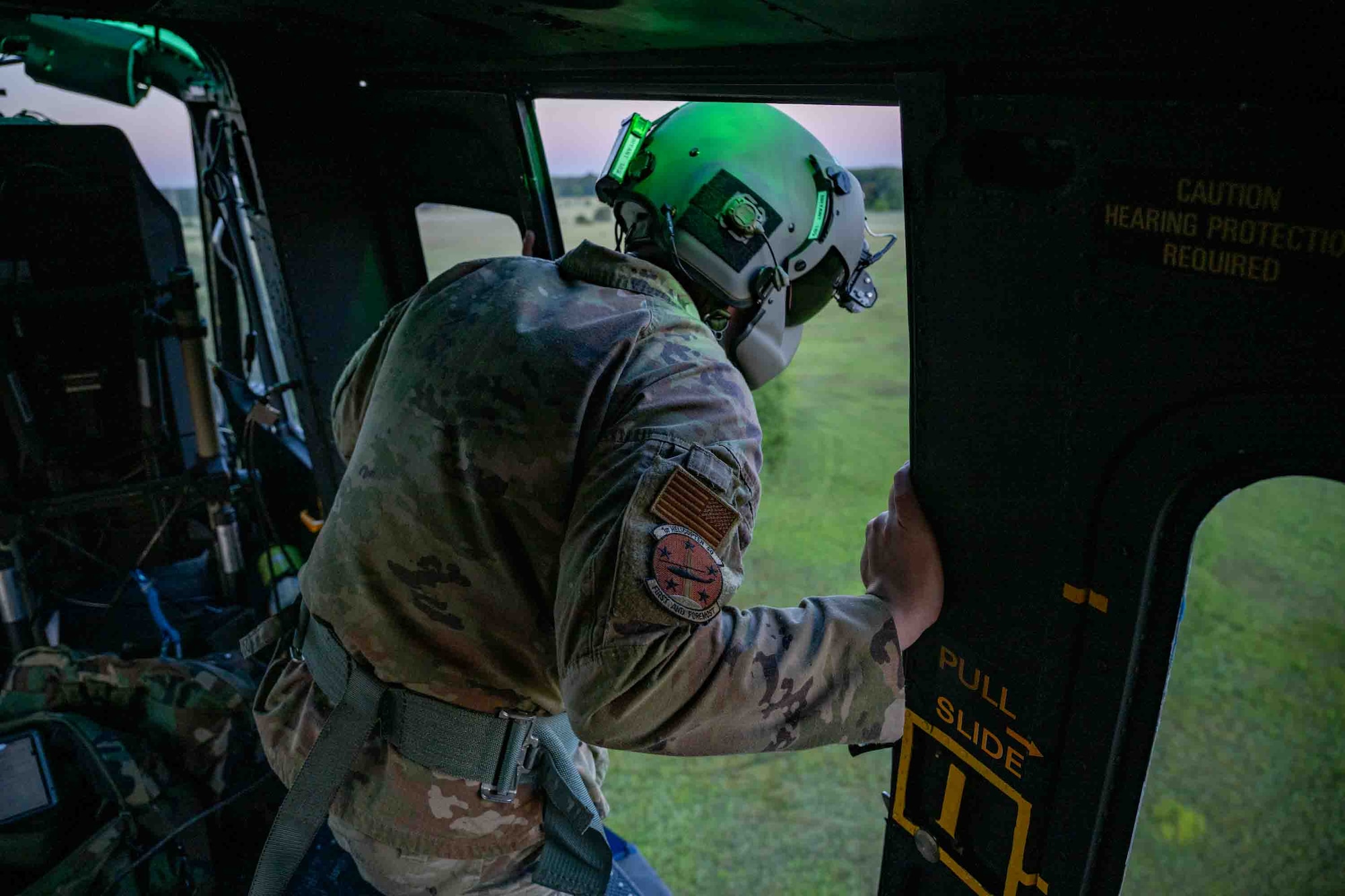 Service members fly in a helicopter.