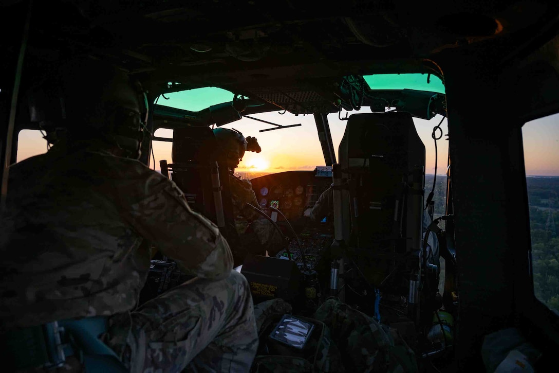 Service members fly in a helicopter.