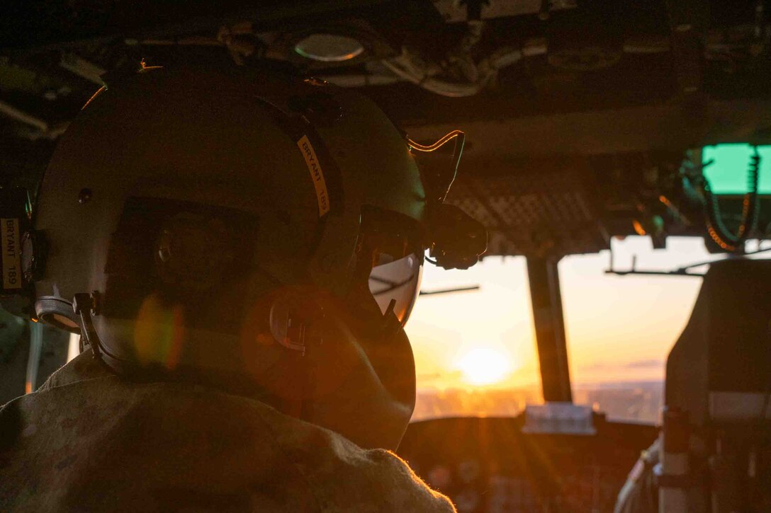 Service members fly in a helicopter.