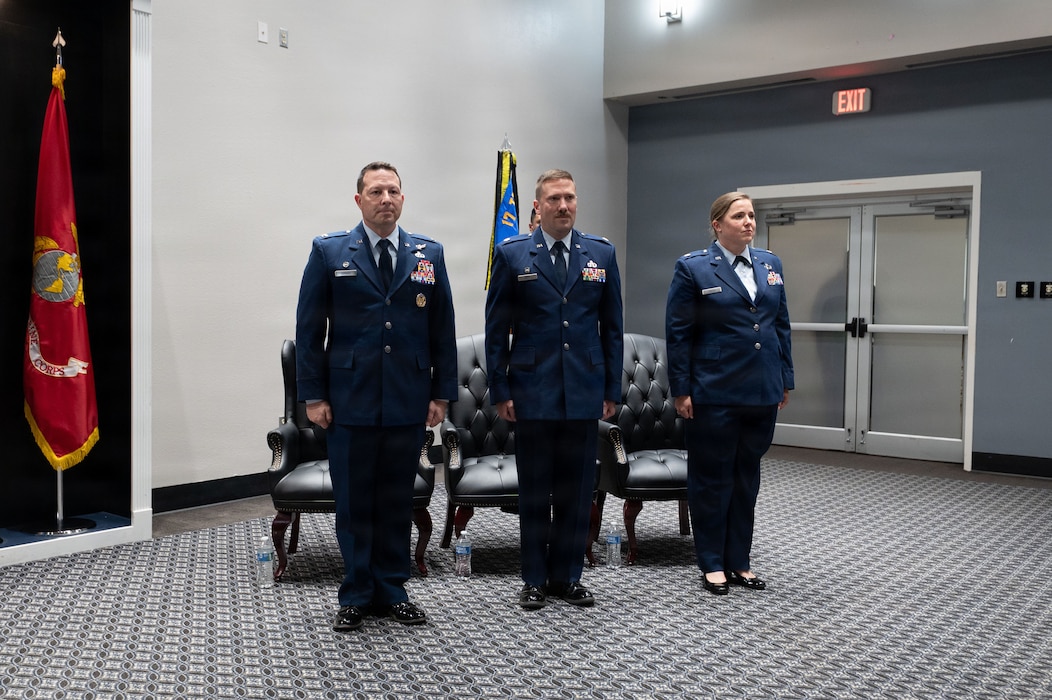 Three service members stand at attention in service dress