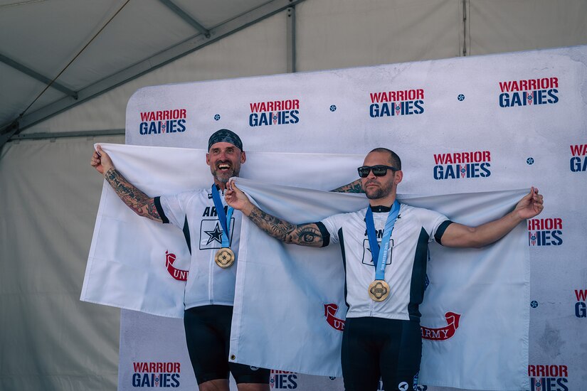 Retired U.S. Army Sgt. 1st. Class Greg Quarles, left, and Staff Sgt. Xavier Rodgers, right, pose for a photo after receiving gold medals for the upright tandem cycling event at the 2026 Warrior Games in San Antonio, Texas, June 14, 2026.