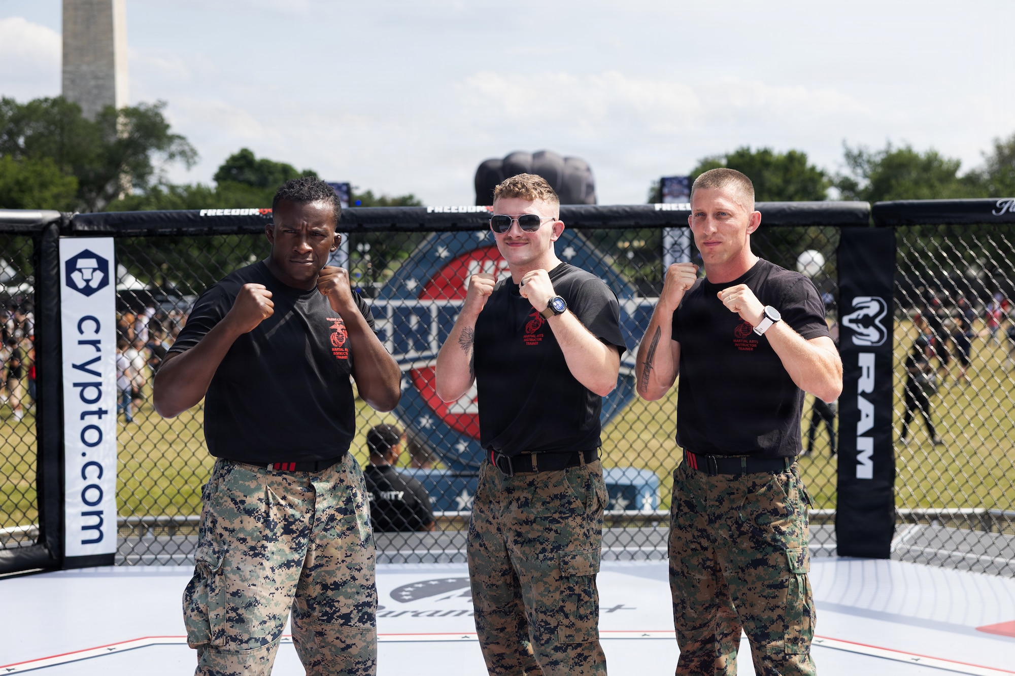 U.S. Marine Sgts. Arkel Brown, Ryan McCartney, and Gunnery Sgt. Jack Pavao pose for photos inside the octagon during the UFC Freedom 250 Fan Fest at the Ellipse in Washington, D.C., June 14, 2026. McCartney represented the Department of War during a combatives showcase highlighting military readiness, discipline, and hand-to-hand combat skills as part of the Freedom 250 celebration. (U.S. Army photo by Sgt. 1st Class Brittany Primavera)