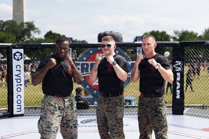 U.S. Marine Sgts. Arkel Brown, Ryan McCartney, and Gunnery Sgt. Jack Pavao pose for photos inside the octagon during the UFC Freedom 250 Fan Fest at the Ellipse in Washington, D.C., June 14, 2026. McCartney represented the Department of War during a combatives showcase highlighting military readiness, discipline, and hand-to-hand combat skills as part of the Freedom 250 celebration. (U.S. Army photo by Sgt. 1st Class Brittany Primavera)