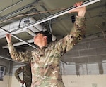 A Soldier from the Illinois Army National Guard’s 123rd Engineer Battalion adjusts a drop ceiling at the Forest Park Armory as part of his annual training in June 2026.