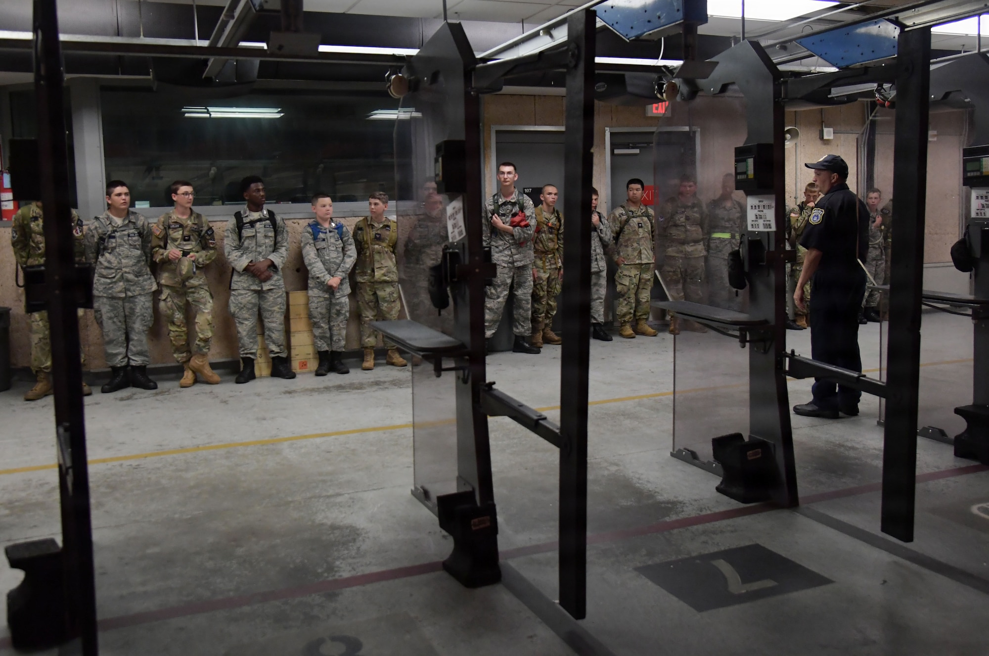 A group of civil air patrol cadets stand shoulder to shoulder inside a combat arms range.