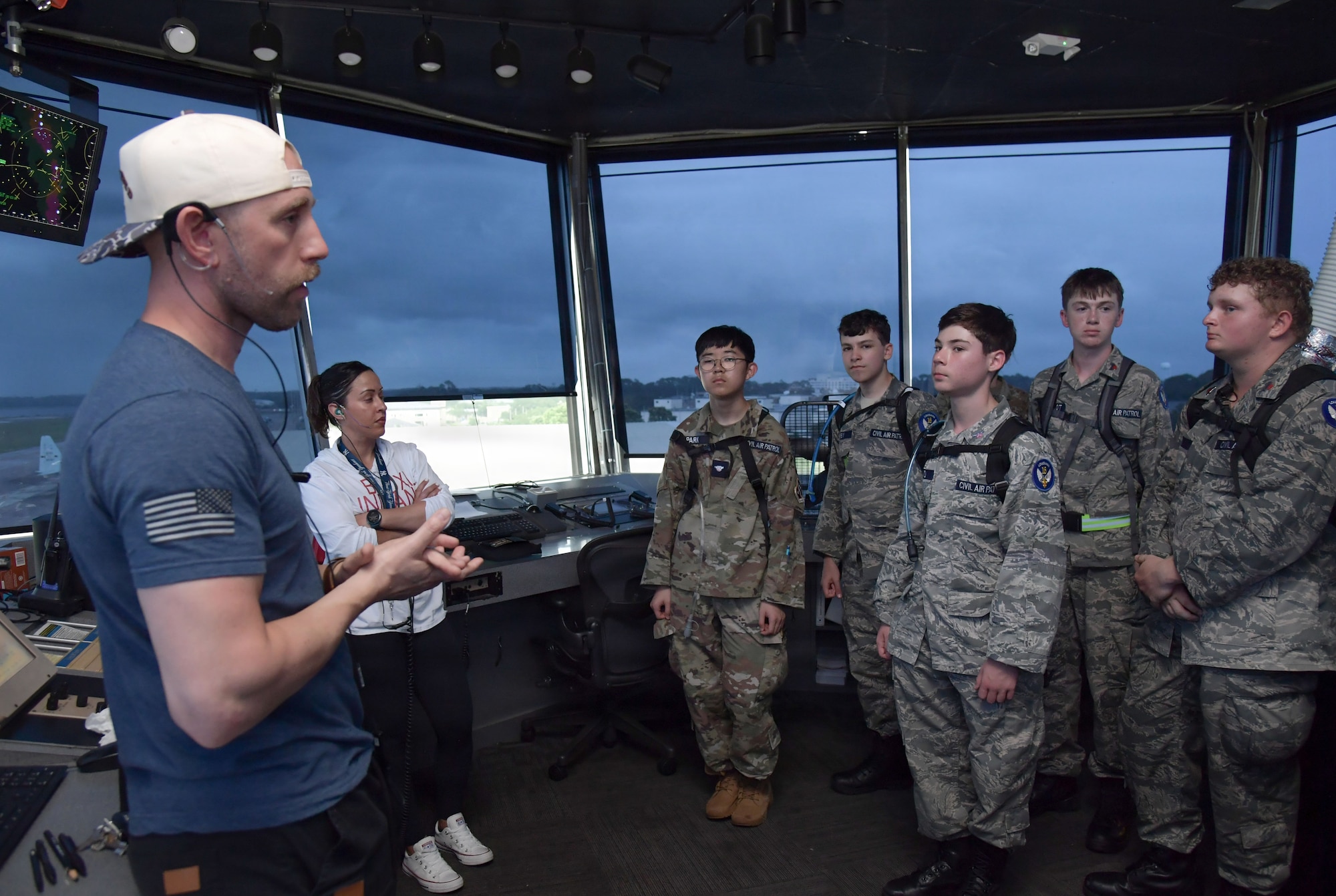 A man speaks to young people in civil air patrol military uniform inside an air traffic control tower.