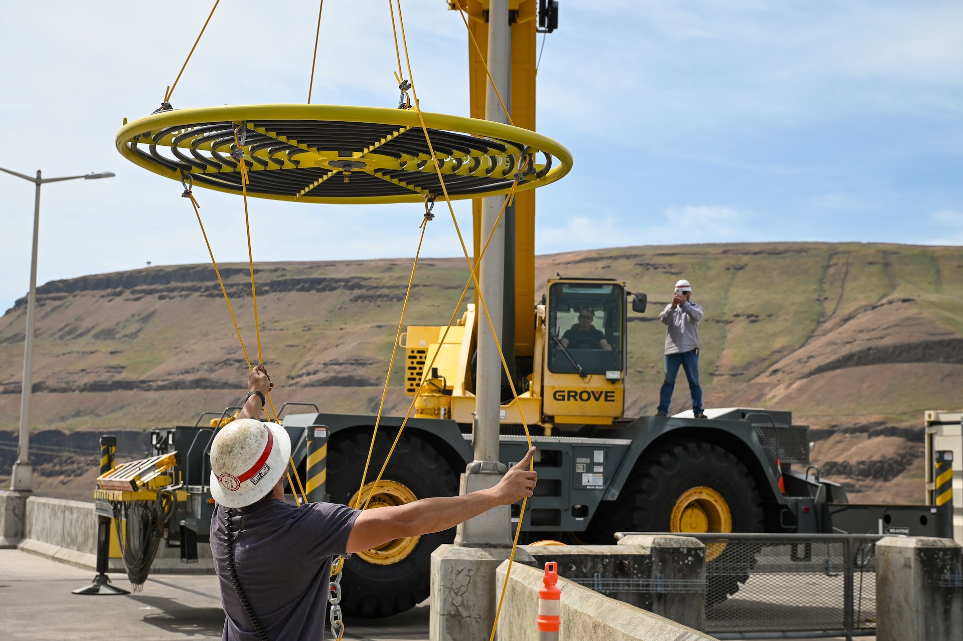 A USACE Walla Walla District employee guides a new bubbler onto a boat for installation. The system cools fish ladders during hot summer months, preventing warm surface water from stalling migrating Pacific salmon.