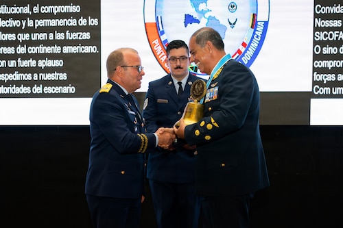 Maj. Gen. Floreal T. Suárez Martínez, commanding general of the Dominican Republic air force, left, transfers the System of Cooperation Among the American Air Forces (SICOFAA) ceremonial bell to Gen. Mario Raúl Contreras León Carty, commanding general of the Peruvian air force during the closing ceremony of the 66th annual Conference of the American Air Chiefs (CONJEFAMER) in Punta Cana, Dominican Republic, June 17, 2026. The transfer signifies Peru's selection as the next host nation and marks the transition to next year's activities. (U.S. Air Force photo by Tech. Sgt. Rachel Maxwell)