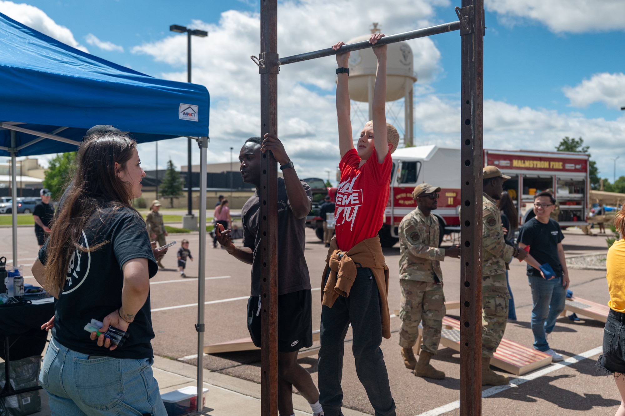 A young boy hangs from a pull-up bar during a dead hang activity.