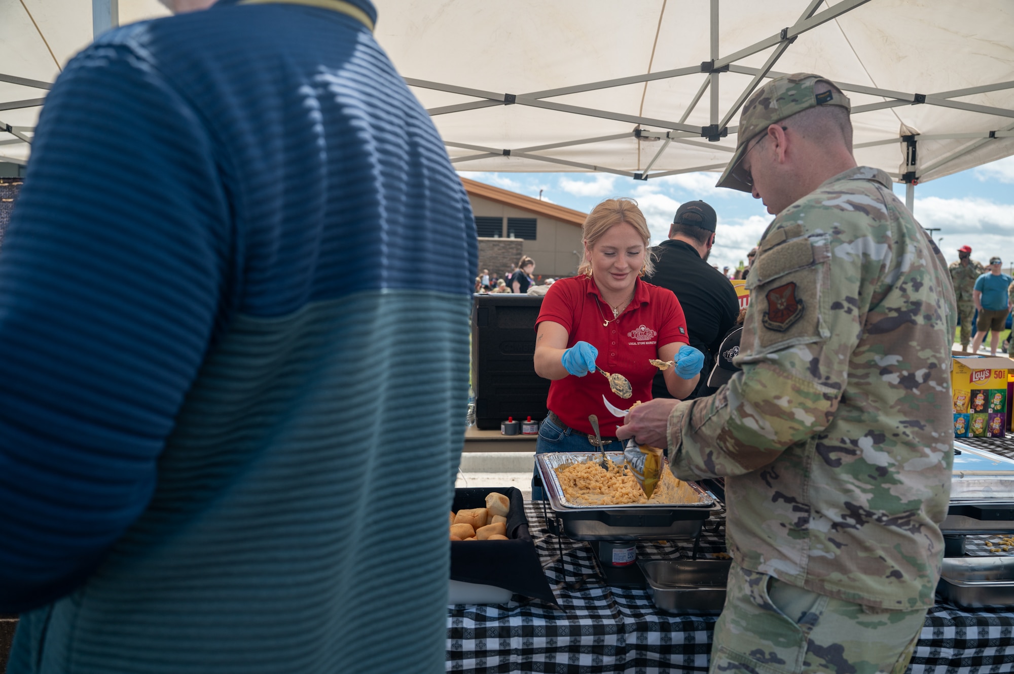 A woman serves food to a uniformed man.