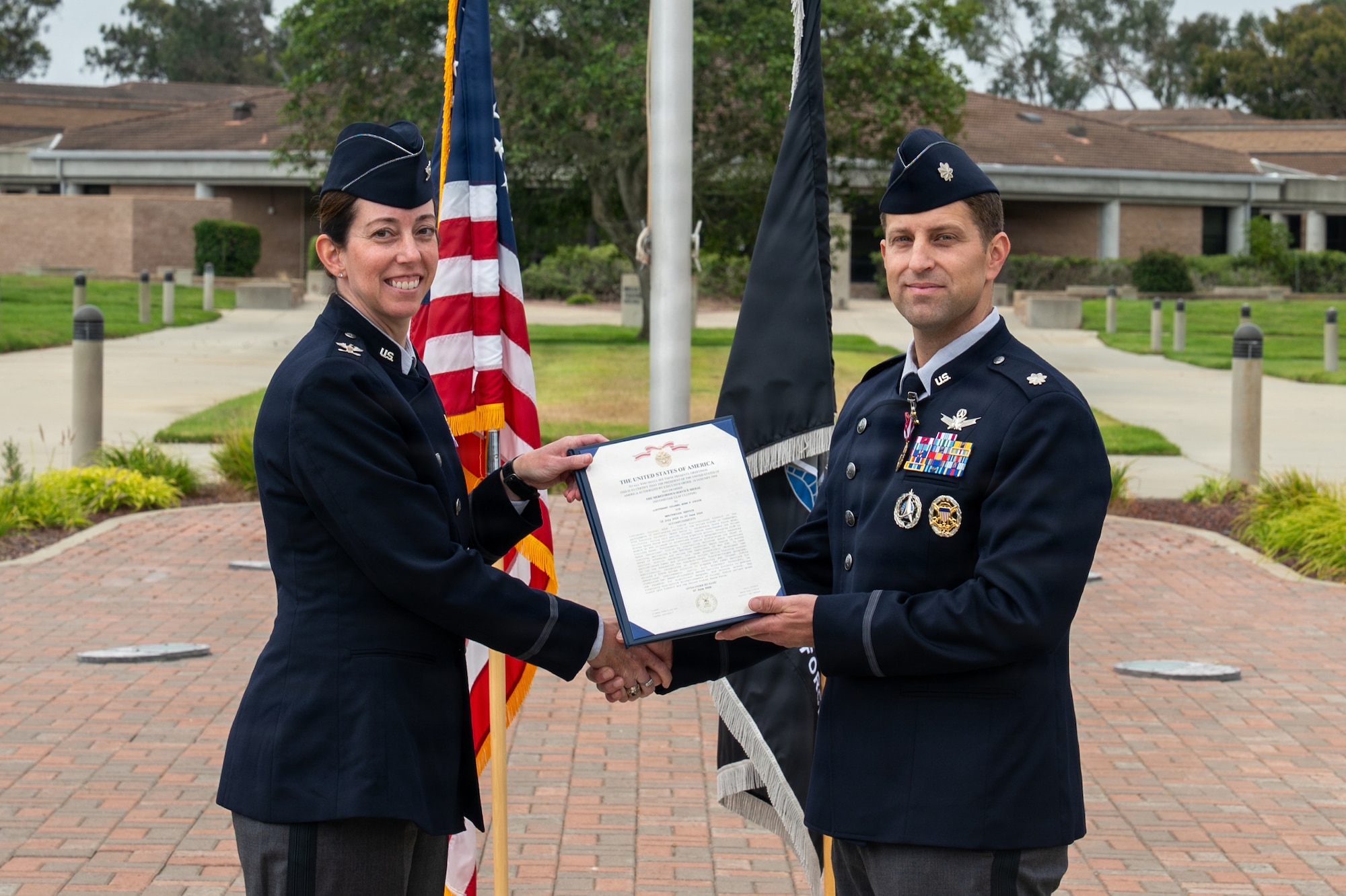 Two people shakes hands as one presents the other an award certificate