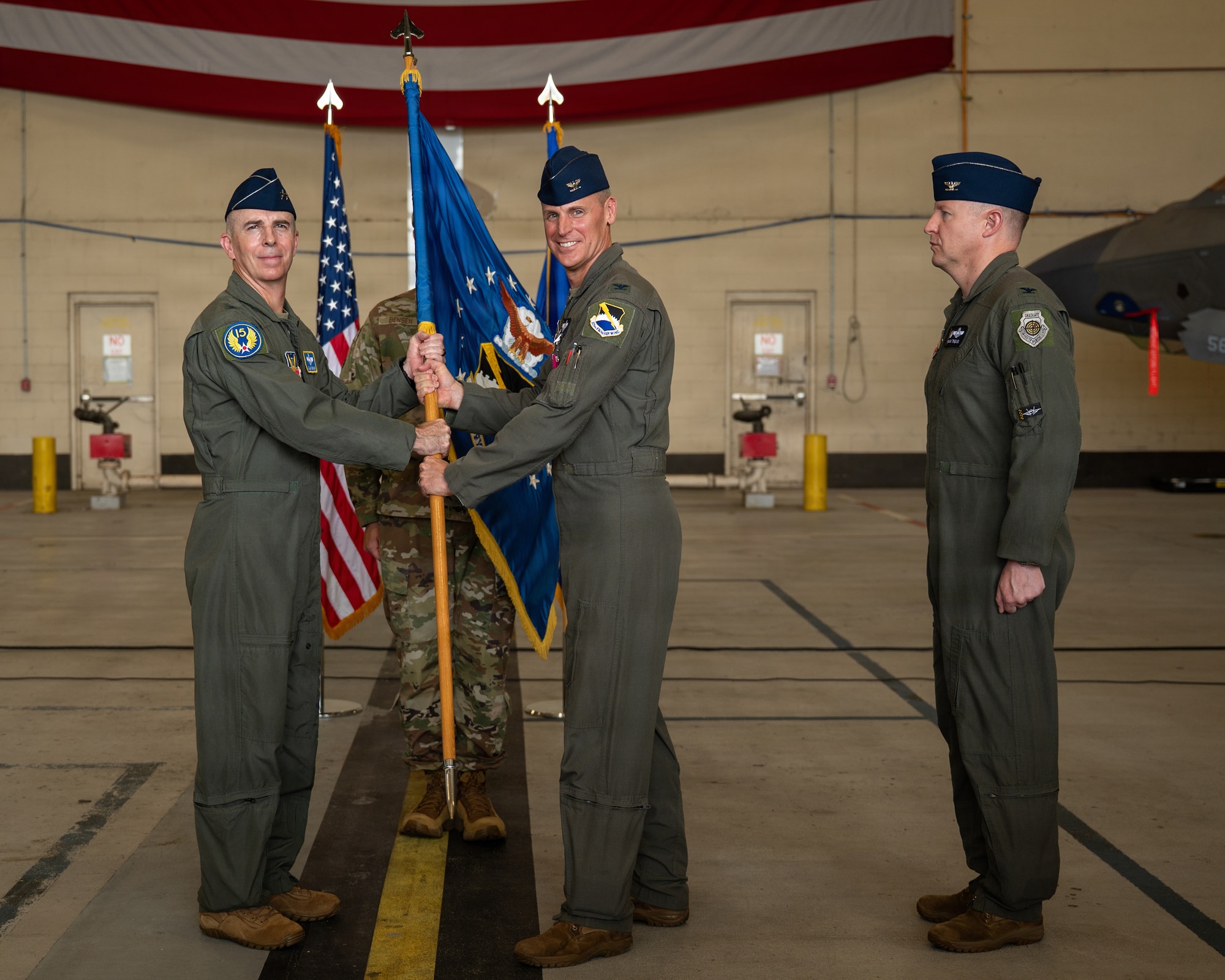 U.S. Air Force Col. Christian Bergtholdt, middle, passes the 325th Fighter Wing guidon to Maj. Gen. Steven Behmer, Fifteenth Air Force commander, during a change of command ceremony at Tyndall Air Force Base, Florida, June 23, 2026. Bergtholdt relinquished command of the 325th FW after two years. (U.S. Air Force photo by Senior Airman Amanda Alvarez)