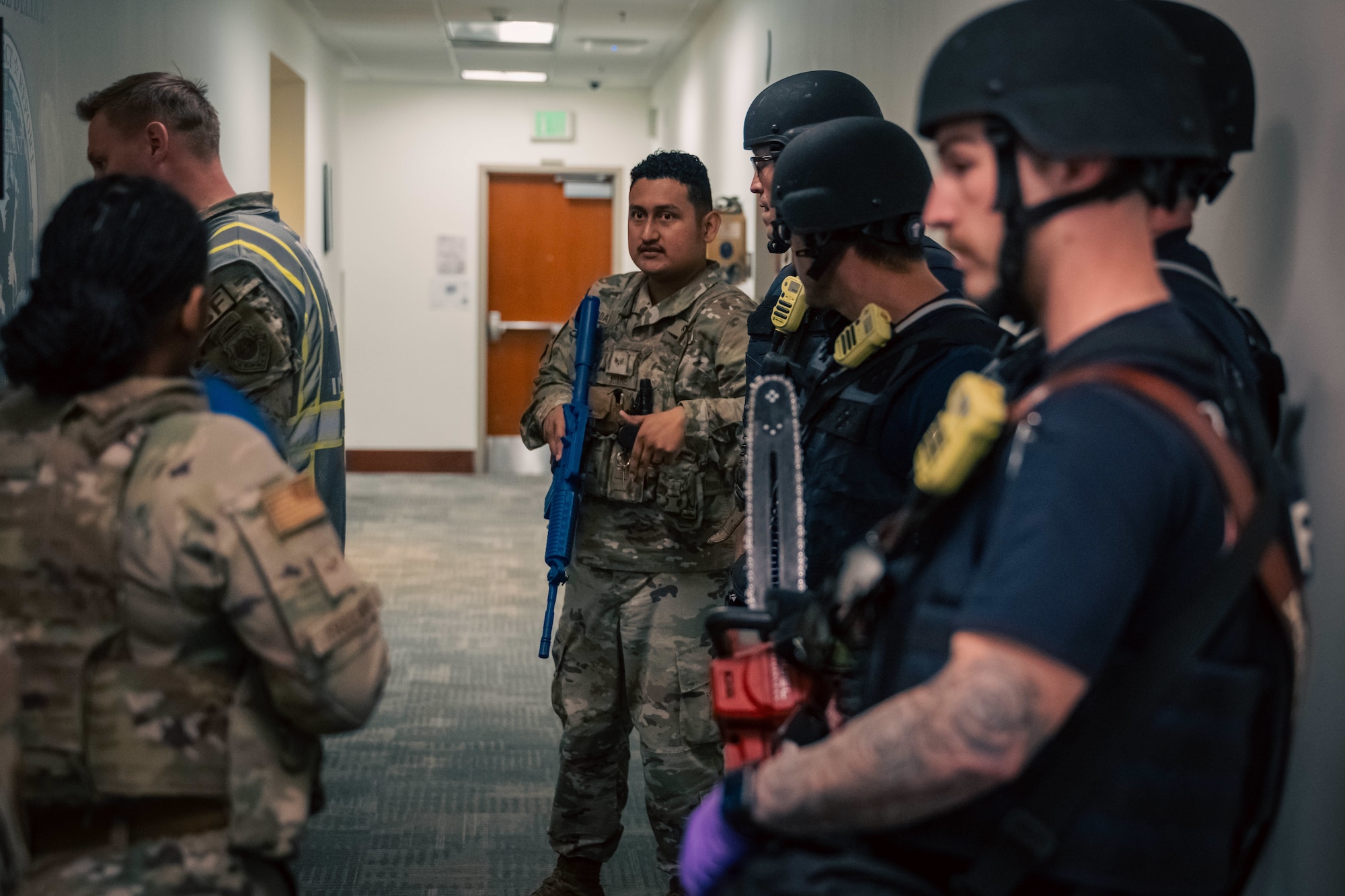 three military members and three fire fighters stand in a hallway