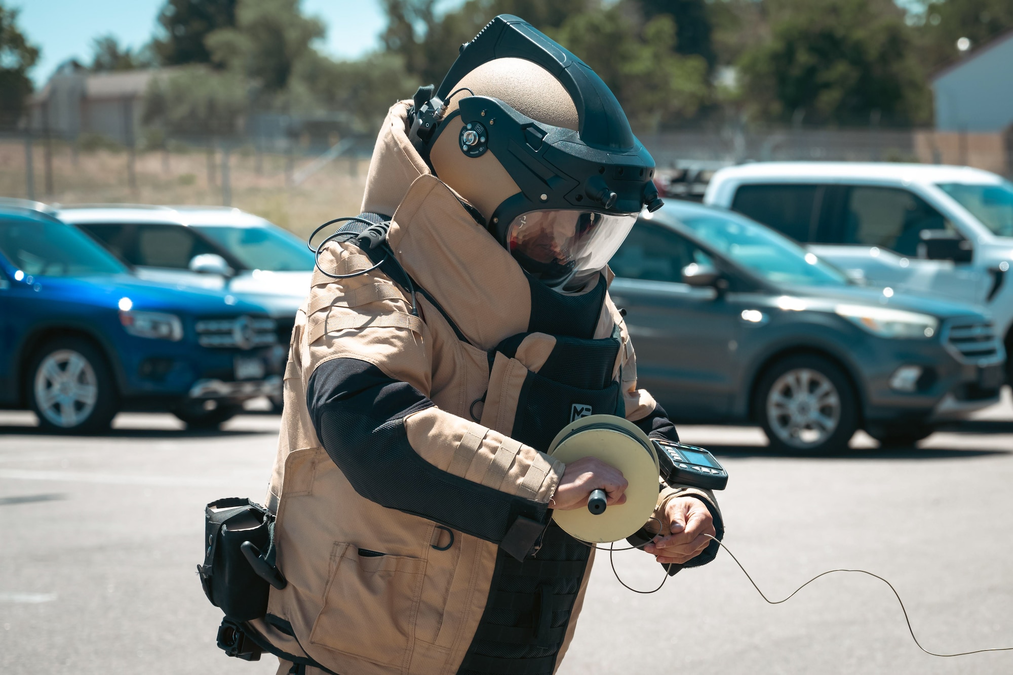 Man in bomb suit reels wire.