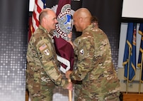 Col. Deon Maxwell, commander of U.S. Army Medical Logistics Command, passes the unit colors to Command Sgt. Maj. Andrew DeCola.