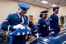 A photo of honor guard members demonstrating a pallbearer ritual inside of a building.
