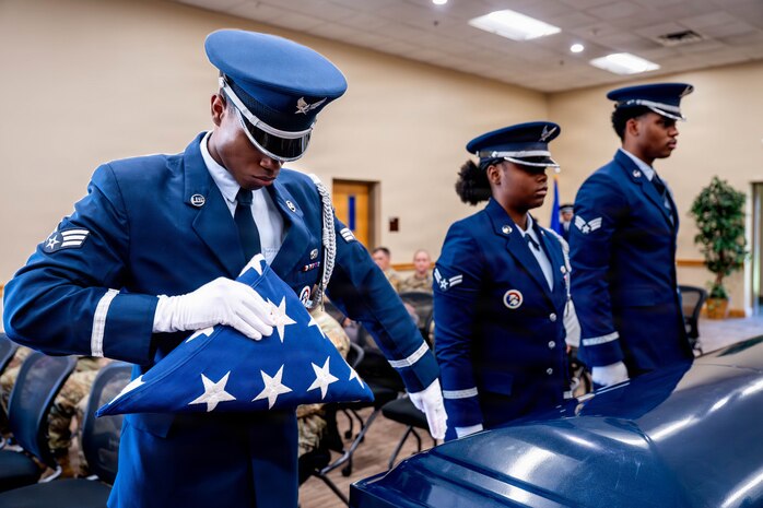 A photo of honor guard members demonstrating a pallbearer ritual inside of a building.
