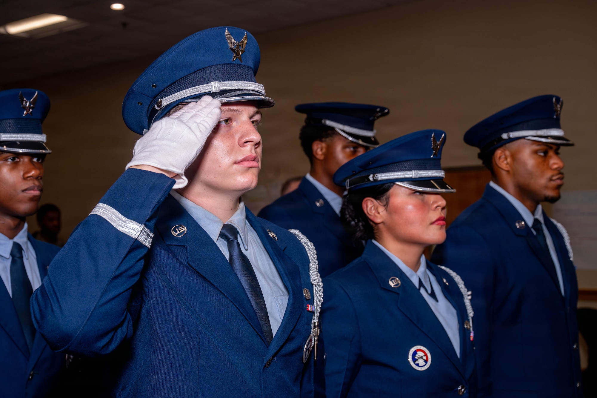 Honor Guard members salute and stand at attention during the national anthem.