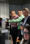 photo of people standing looking at people working on computers