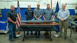 Members of Naval Surface Warfare Center, Carderock Division's Fabrication and Technical Support Division pose with a scale model of the proposed future battleship USS Defiant (BBG 1) in the Subtractive and Additive Manufacturing Branch model shop in West Bethesda, Maryland.