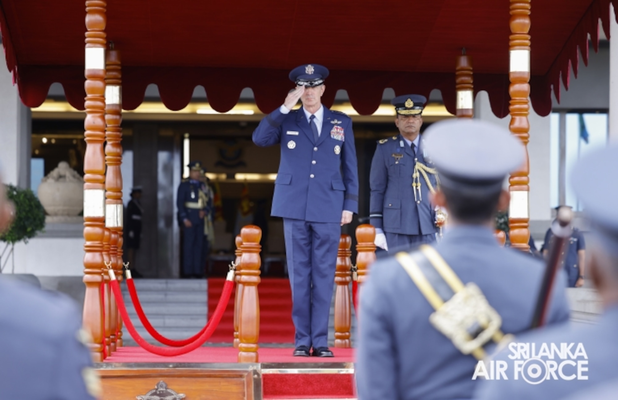 A senior military leader in formal dress salutes a formation.