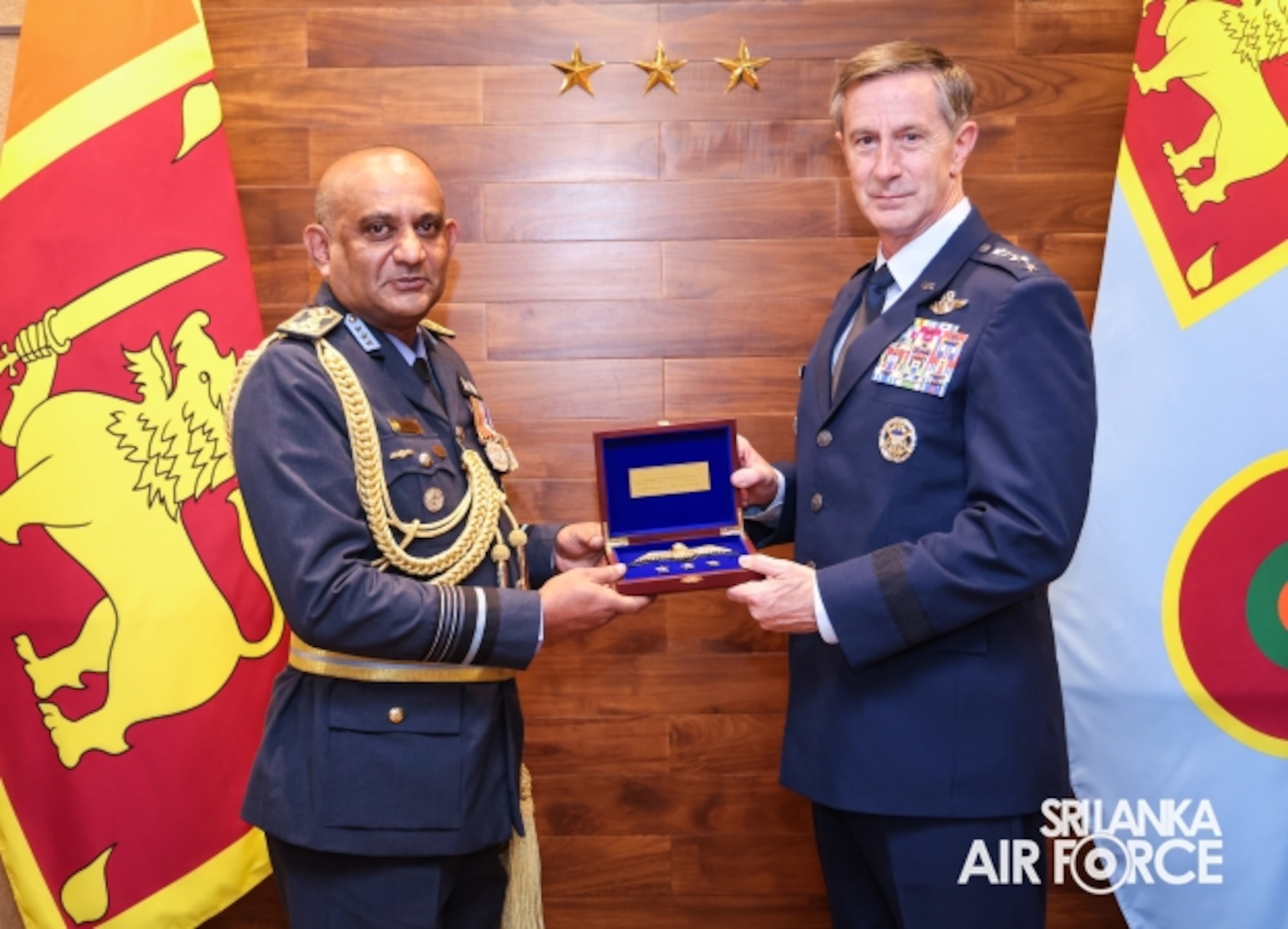 Two generals pose for a photo while holding a box between them.