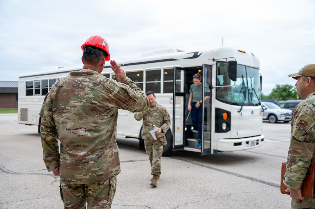 A service member salutes another service member coming out of a bus