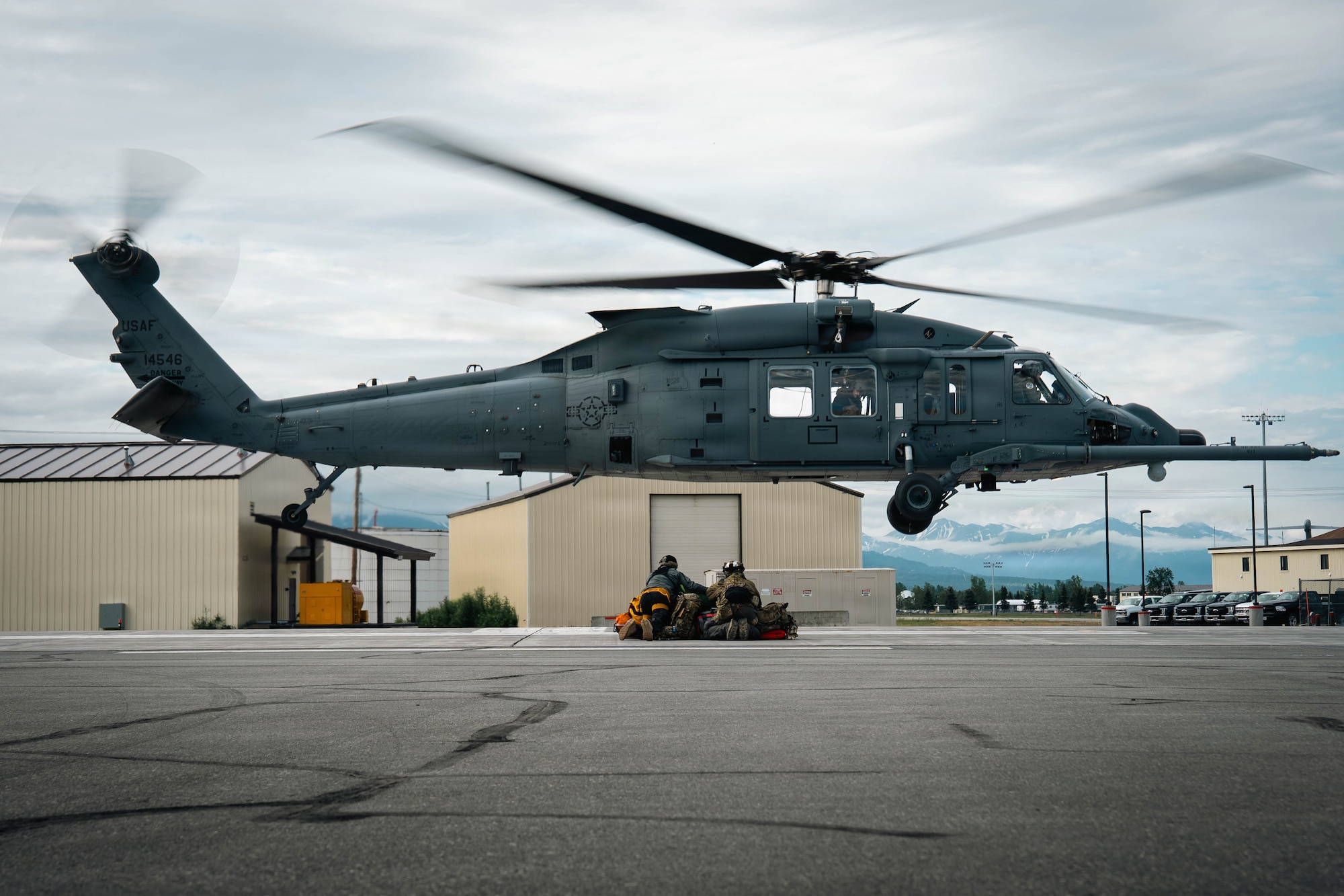 U.S. Air Force Tech. Sgt. Allenmikel Armstrong and Master Sgt. Daniel Stikeleather, 212th Rescue Squadron pararescuemen, protect medical and safety equipment whilst an HH-60W Jolly Green II takes off during the Arctic Thunder Open House 26 full-scale exercise on Joint Base Elmendorf-Richardson, Alaska, June 17, 2026. The exercise simulated a recovery operation of a pilot after an aircraft incident. (U.S. Air Force photo by Airman 1st Class Keola Vischi)