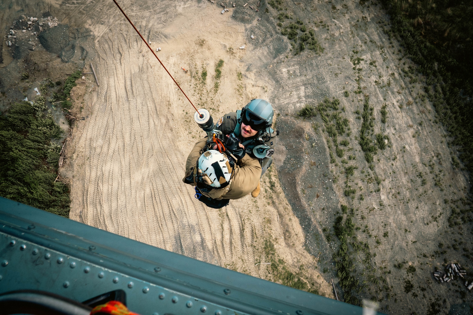 U.S. Air Force Master Sgt. Daniel Stikeleather, 212th Rescue Squadron pararescueman, and a simulated casualty are hoisted into an HH-60W Jolly Green II during the Arctic Thunder Open House 26 full-scale exercise on Joint Base Elmendorf-Richardson, Alaska, June 17, 2026. The exercise simulated a recovery operation of a pilot after an aircraft incident. (U.S. Air Force photo by Airman 1st Class Keola Vischi)