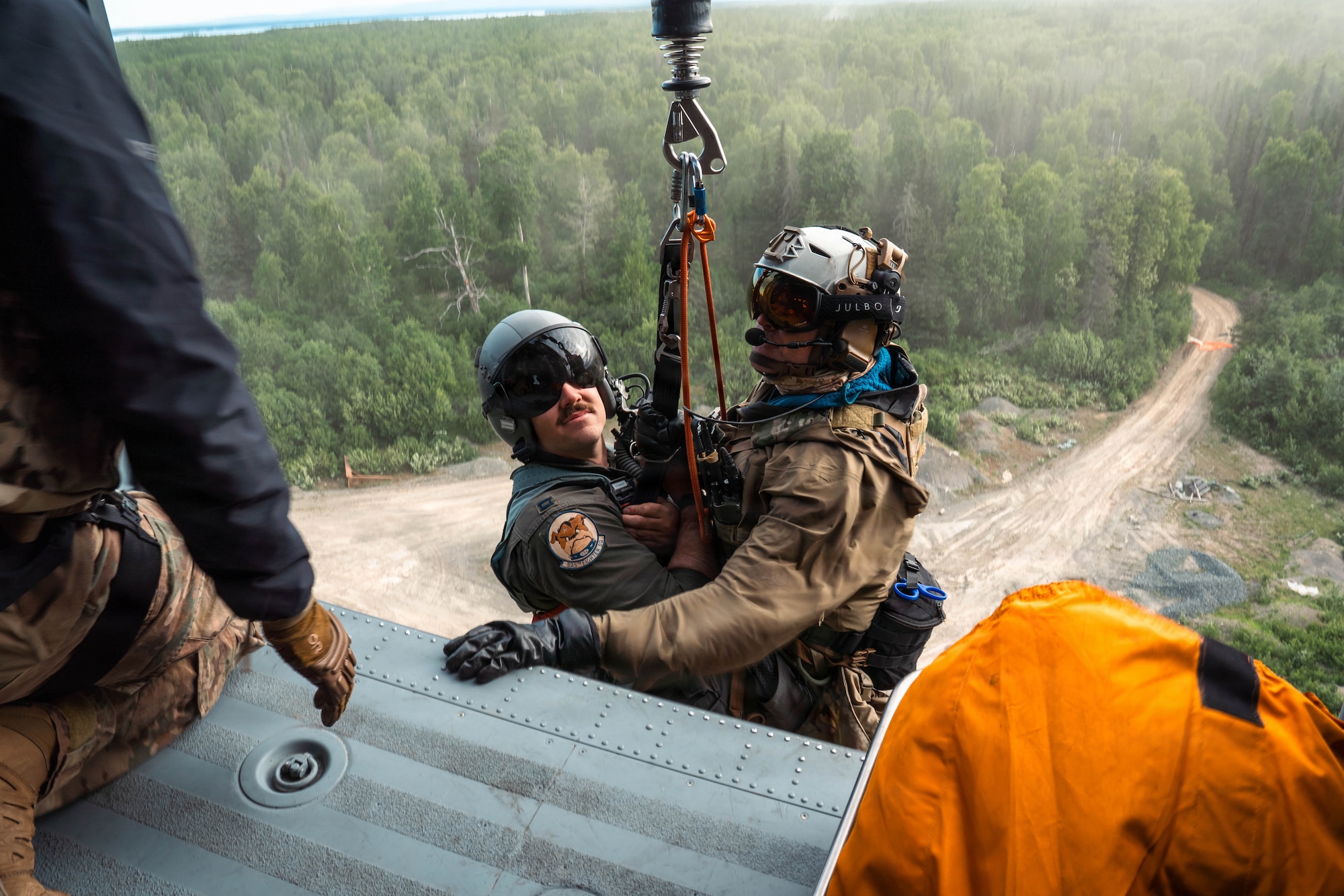 U.S. Air Force Master Sgt. Daniel Stikeleather, 212th Rescue Squadron pararescueman, and a simulated casualty are hoisted into an HH-60W Jolly Green II during the Arctic Thunder Open House 26 full-scale exercise on Joint Base Elmendorf-Richardson, Alaska, June 17, 2026. The exercise simulated a recovery operation of a pilot after an aircraft incident. (U.S. Air Force photo by Airman 1st Class Keola Vischi)