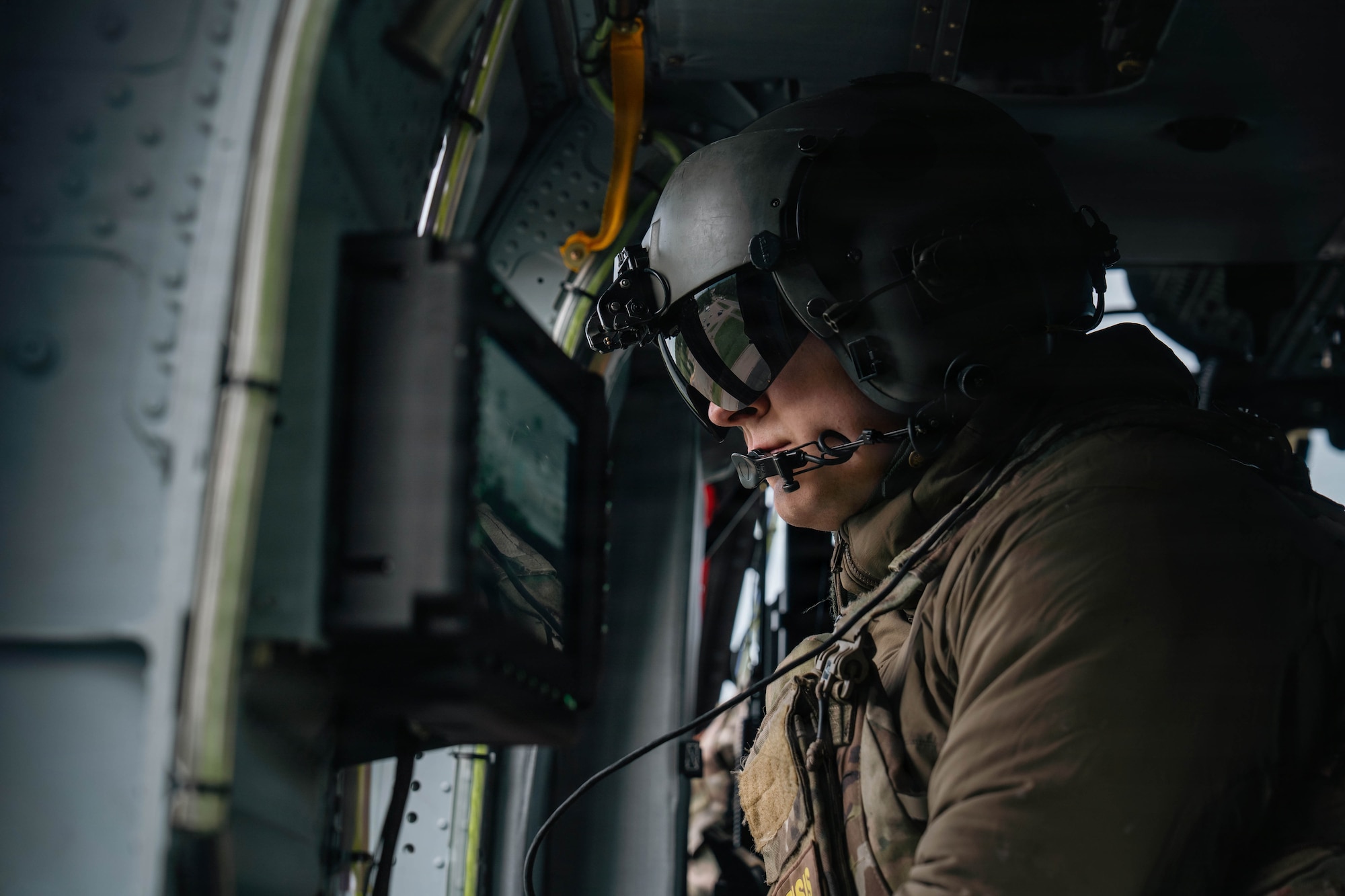 U.S. Air Force Tech. Sgt. Peter Reddington, 210th Rescue Squadron special mission aviator, looks out of the window of an HH-60W Jolly Green II during the Arctic Thunder Open House 26 full-scale exercise on Joint Base Elmendorf-Richardson, Alaska, June 17, 2026. The exercise simulated a recovery operation of a pilot after an aircraft incident. (U.S. Air Force photo by Airman 1st Class Keola Vischi)