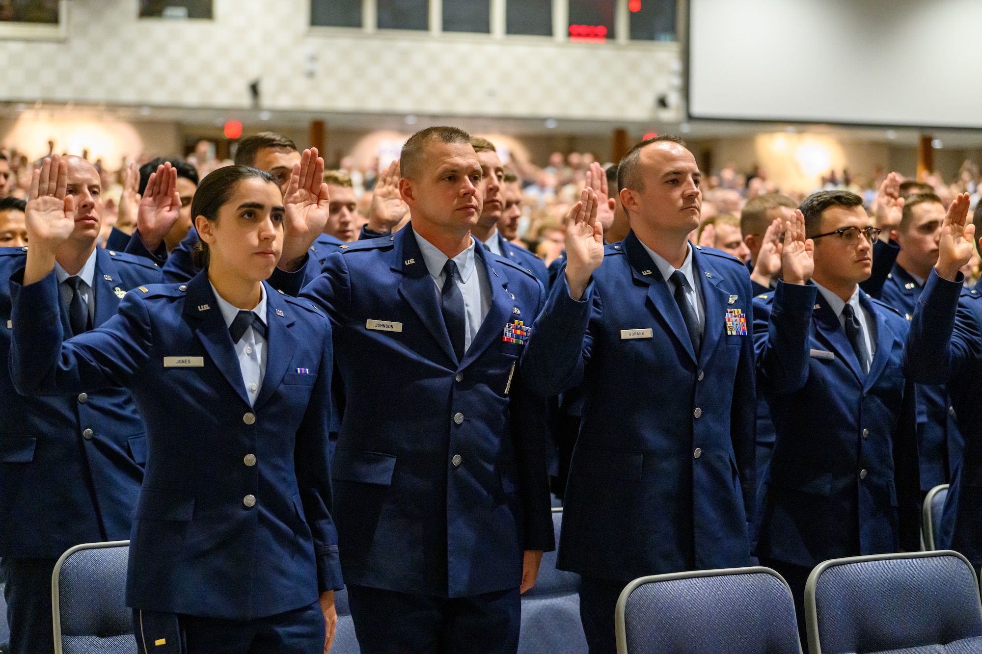 A group of servicemembers raise their hand to recite the oath of office during a  graduation ceremony
