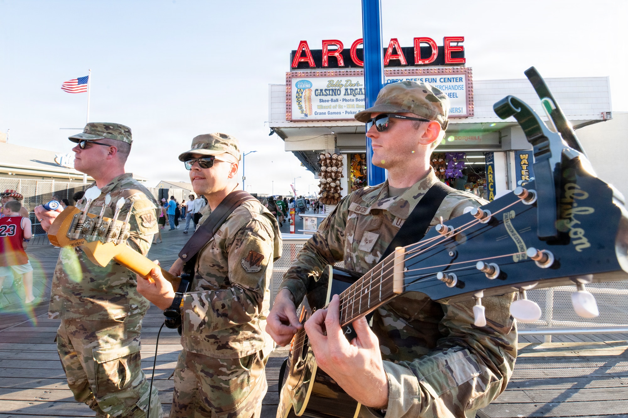 (From left to right) U.S. Air Force Heritage of America Band members Tech. Sgt. Cody Peterson, assistant director of operations; Staff Sgt. Simon Evans, bassist; and Senior Airman Michael Gatch, guitarist, perform on the boardwalk in Wildwood, New Jersey, June 19, 2026.