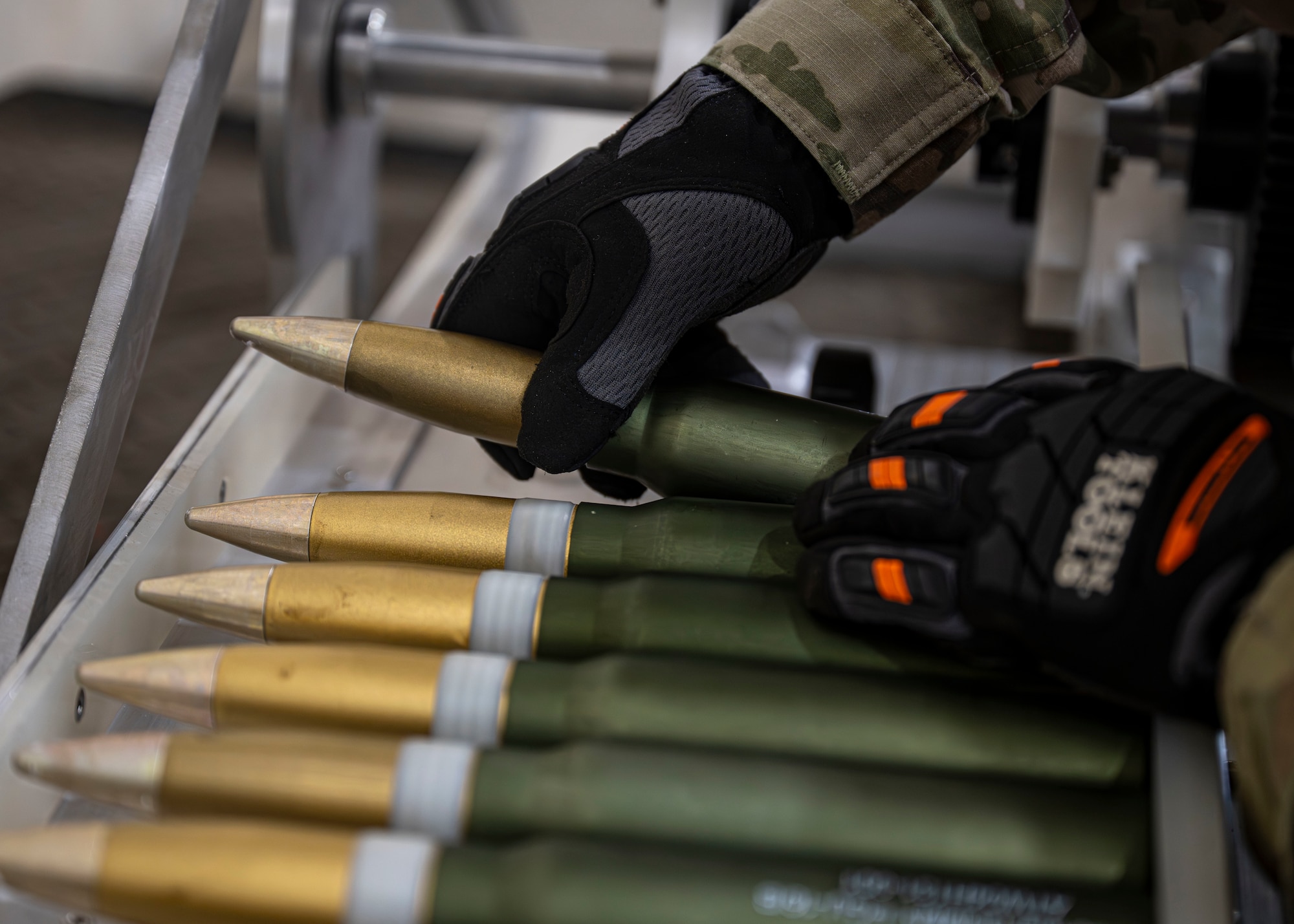 A munitions specialist assigned to the 1st Special Operations Wing puts 30 mm rounds in an ammunition-linking machine
