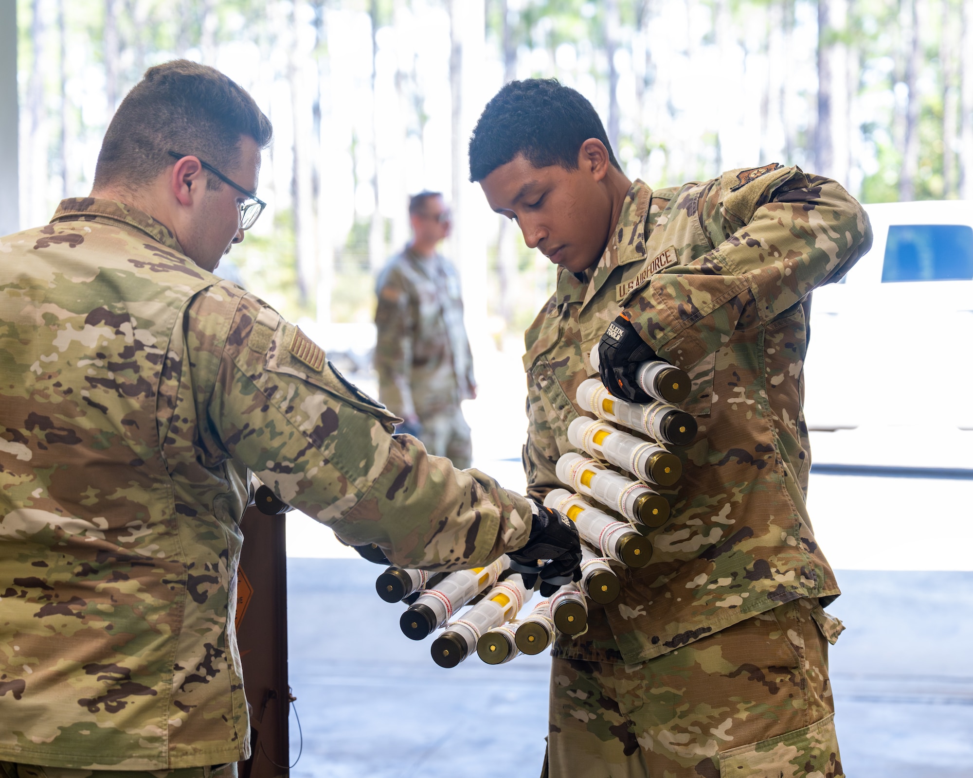 Munitions specialists assigned to the 1st Special Operations Wing examine 30 mm rounds during training on a new ammunition linking machine